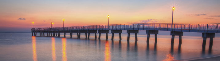 Wharf in Delaware reflecting the water and pastel orange pink sunset