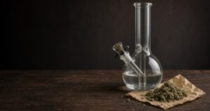 Clean glass bong with bowl packed beside ground cannabis