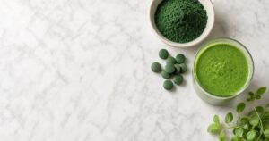 Chlorella powder and tablets flat lay with green smoothie
