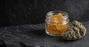 Live resin concentrate jar with frosty cannabis flower nearby