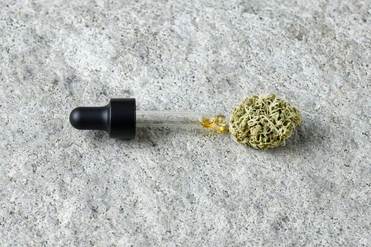 Oil dropper beside a hemp flower