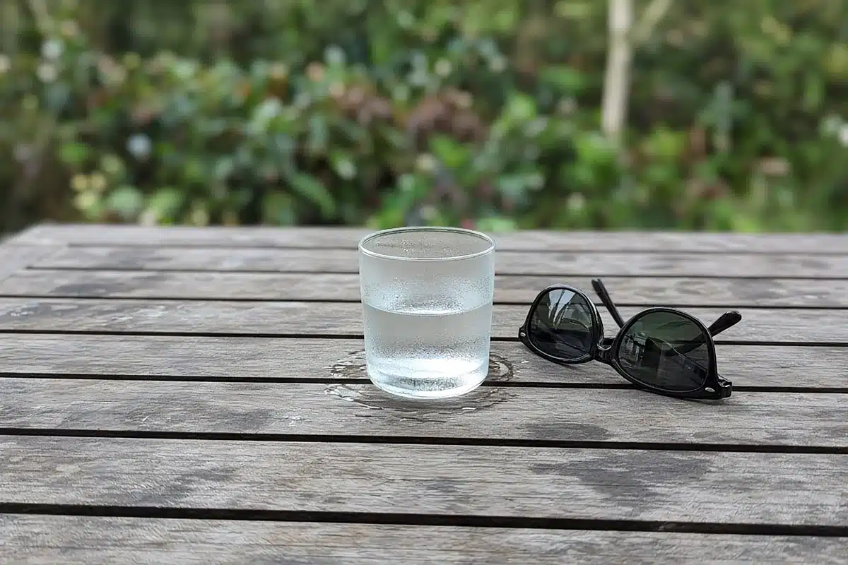 Glass of water and sunglasses on a patio table
