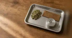 Rolling tray with ground cannabis flower, a hemp wrap and a metal grinder